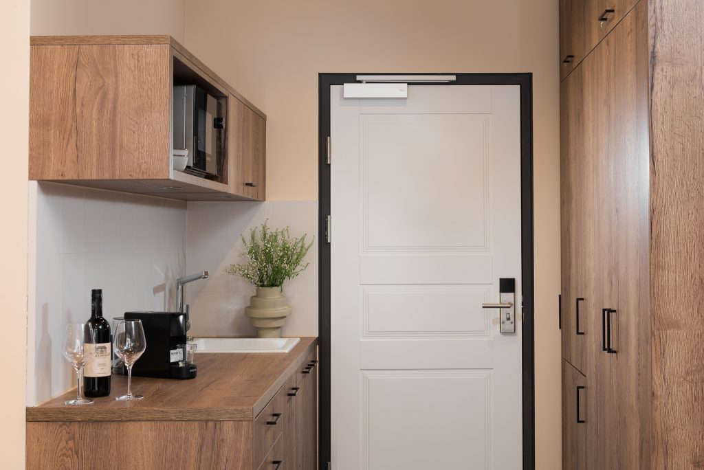 Entrance of the studio apartment at master Linzergasse, showcasing a sleek door and a modern kitchenette