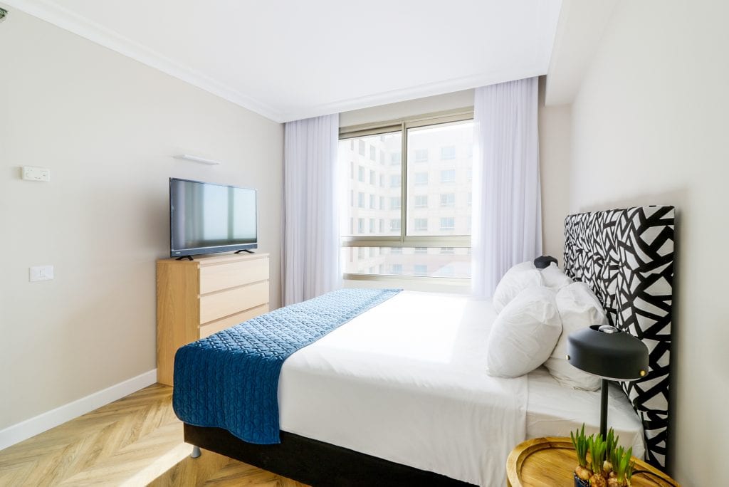 Bright and spacious bedroom in the Two-Bedroom Seaview Apartment at master Haifa, designed for relaxation with soft linens and stylish decor.