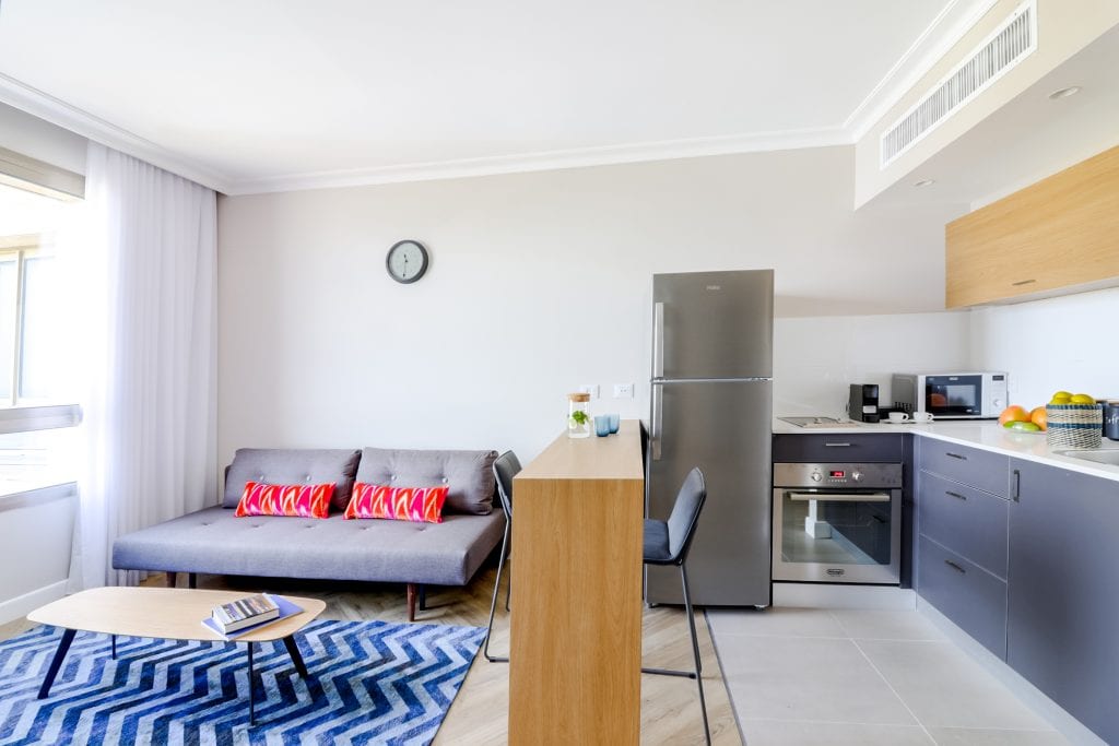 Well-appointed living room in the One-Bedroom Seaview Apartment at master Haifa, blending comfort with a sleek, modern design.