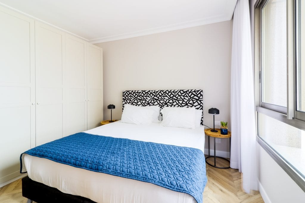 Comfortable bedroom in the One-Bedroom Seaview Apartment at master Haifa, featuring a plush bed and a warm, inviting ambiance.
