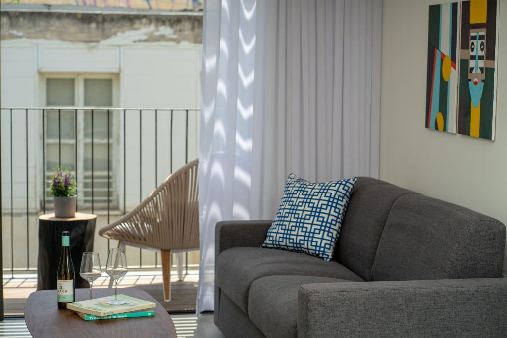 Bright and modern living space in the Four-Bedroom Apartment with Balcony at master Shenkin Tel Aviv, seamlessly connecting to the outdoor balcony.