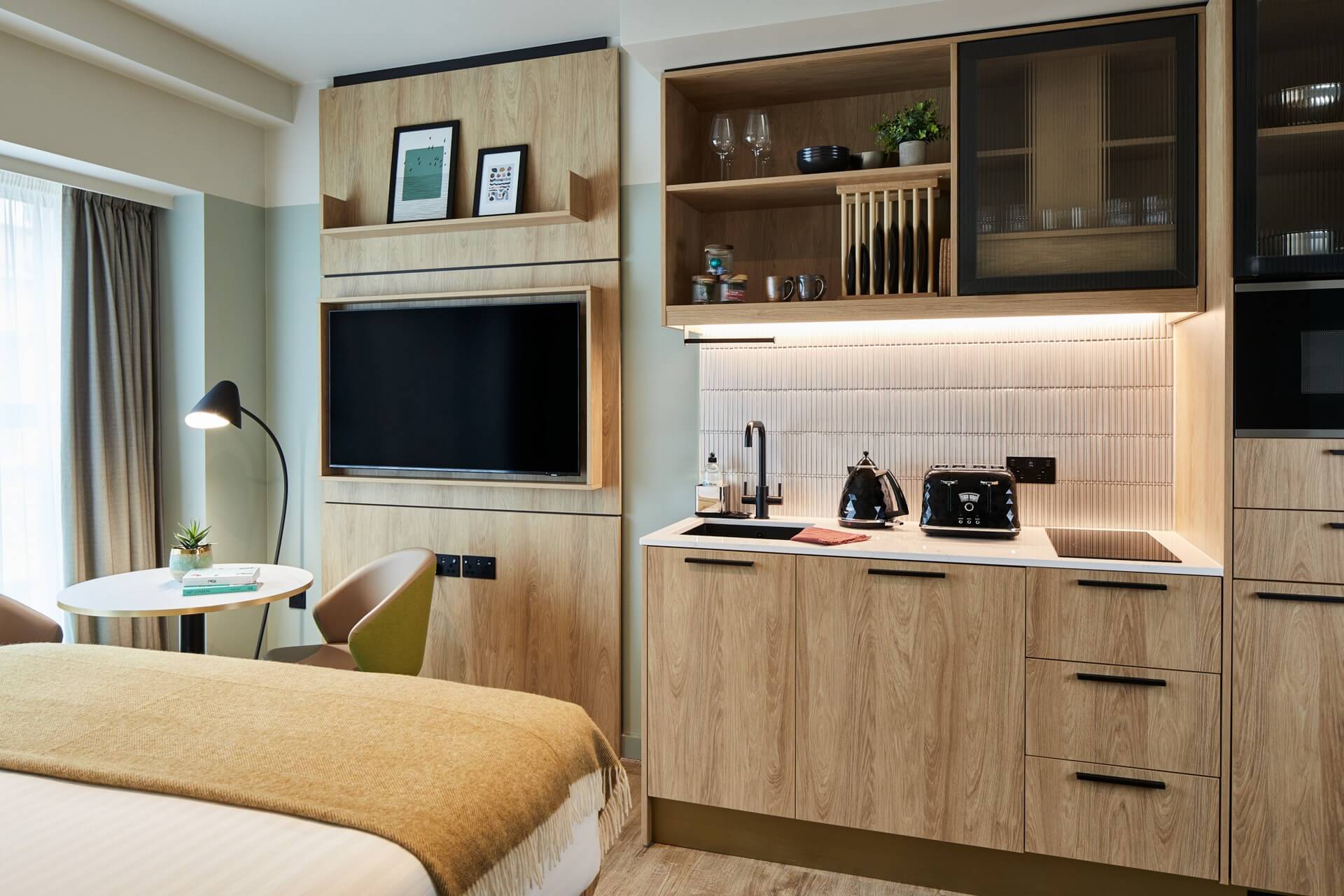 Bright and inviting Studio at master St. Paul’s London, blending a stylish sleeping area, kitchenette, and a dining setup with two chairs.