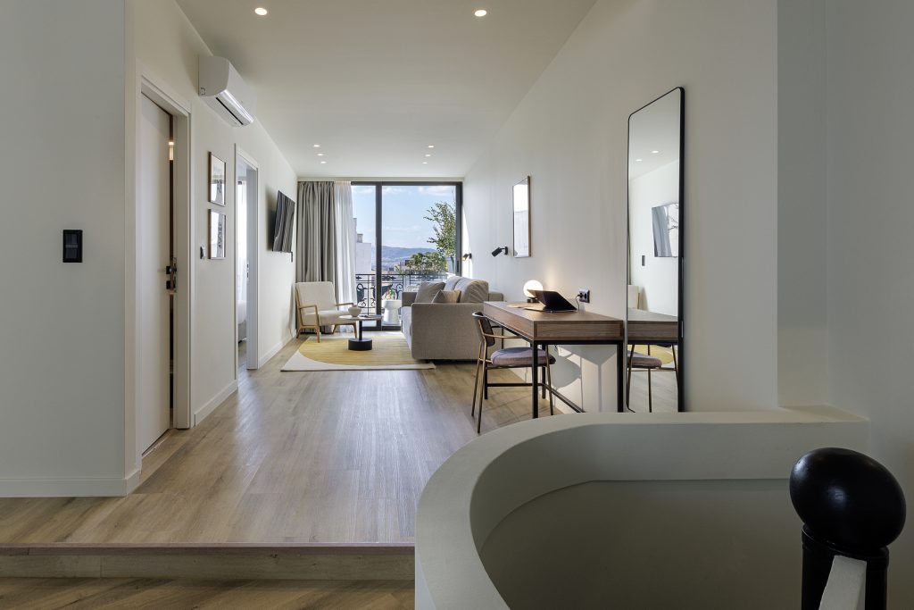 Bright and stylish living space in the One Bedroom Penthouse at master Plaka Athens, seamlessly connecting the cozy sofa area to the outdoor balcony.