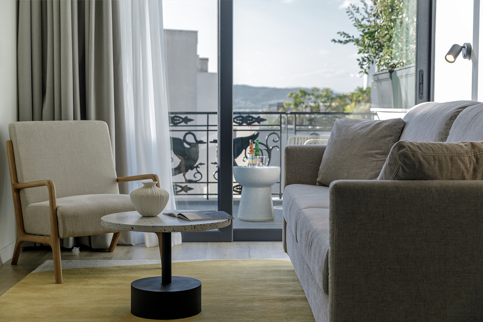Elegant seating area in the One Bedroom Penthouse at master Plaka Athens, featuring a cozy sofa and access to a private balcony with city views