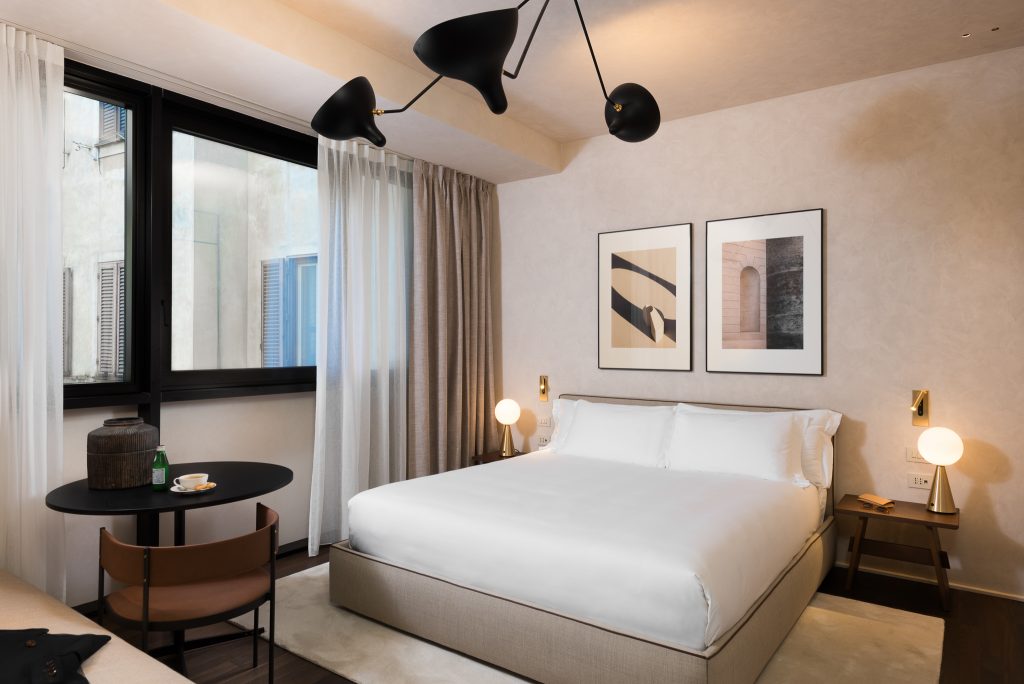 Comfortable bed in the Family Apartment with Balcony at master Trevi Rome, positioned next to a sunlit balcony for a relaxing ambiance.