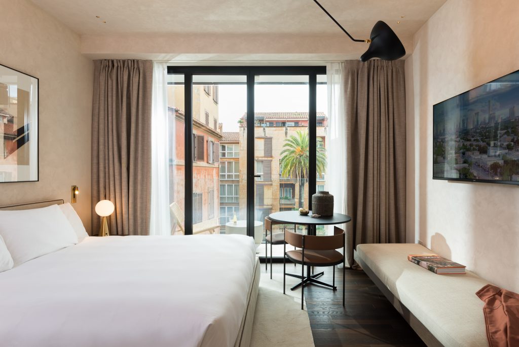 Bright and inviting bedroom in the Family Apartment with Balcony at master Trevi Rome, featuring a cozy bed and access to a private balcony with city views