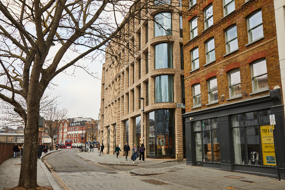 Curved street view near master Farringdon London serviced apartments, with pedestrians, red buses, and historic buildings creating an urban atmosphere.