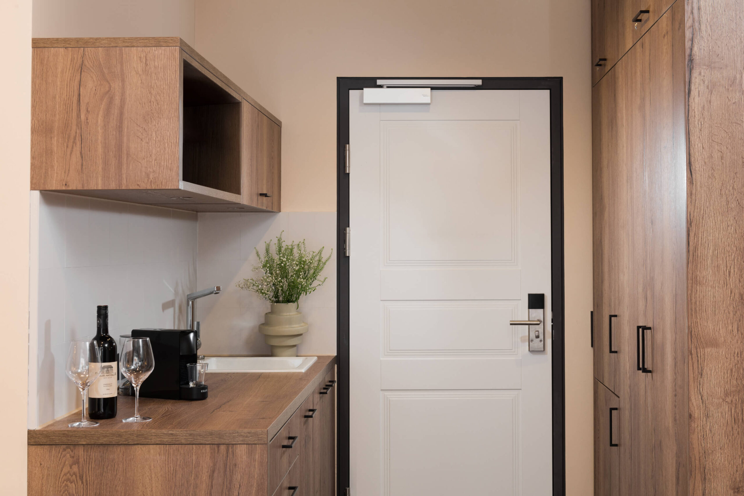 Entrance of the studio apartment at master Linzergasse, showcasing a sleek door and a modern kitchenette