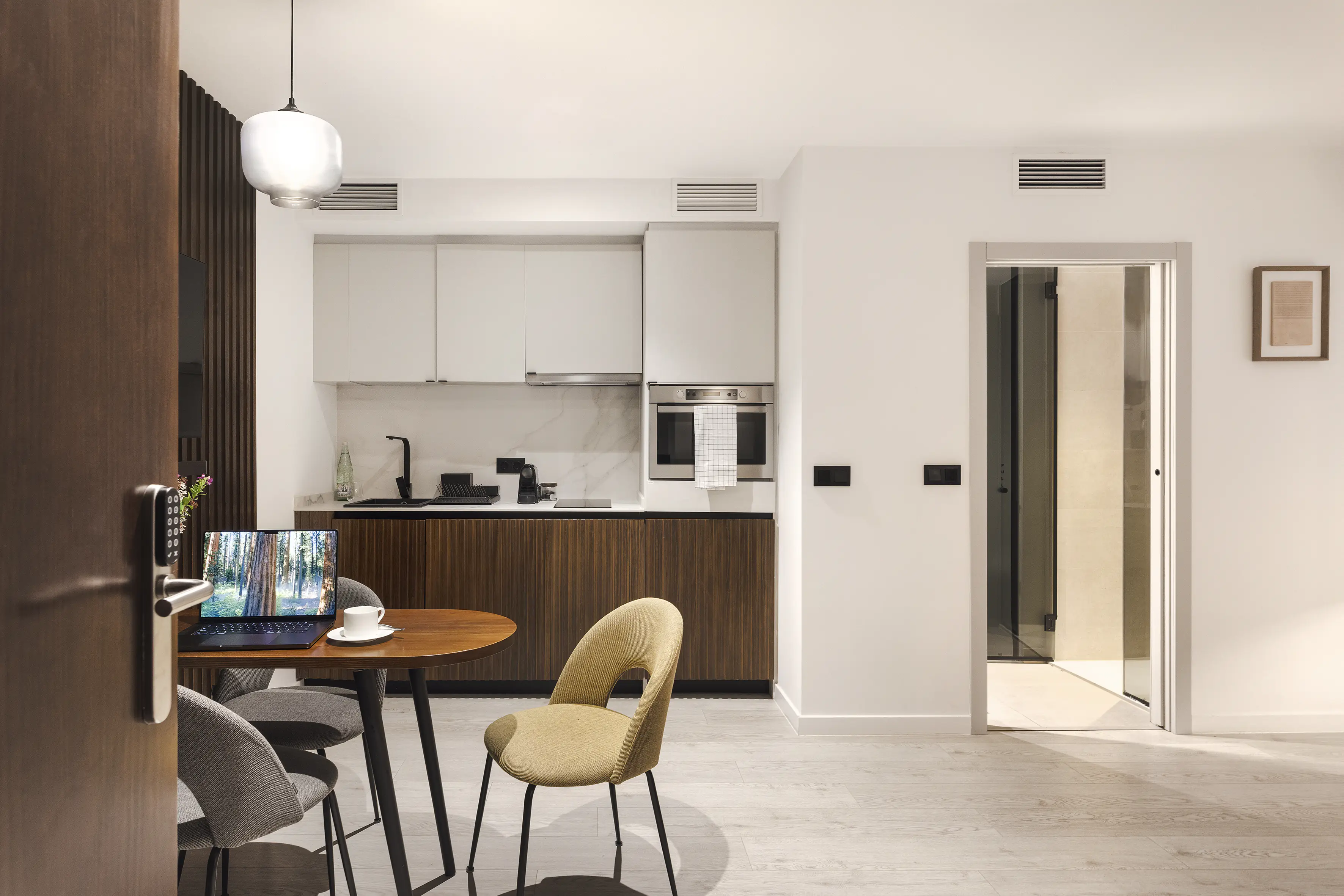 Interior One Bedroom Apartment at master La Rambla Barcelona featuring modern kitchen, dining table, and laptop workspace.